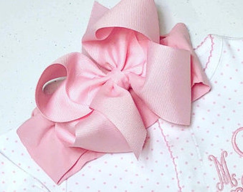 May include: A pink satin bow headband. The headband is made of a soft, stretchy material and is perfect for adding a touch of elegance to any outfit.