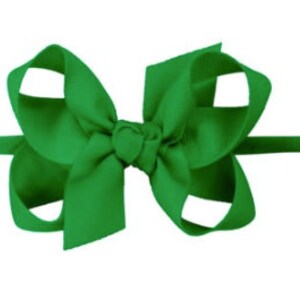 May include: A green hair bow with a simple, classic design. The bow is made of a soft, smooth fabric and is attached to a stretchy headband.