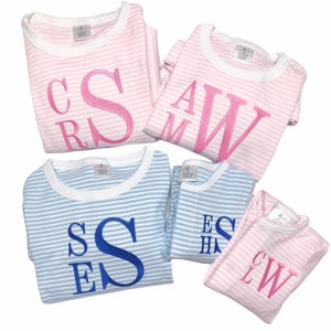 Puede incluir: Cuatro pijamas a rayas con iniciales bordadas personalizadas. Dos pijamas son rosas con rayas blancas y dos son azules con rayas blancas. Las iniciales est&aacute;n en hilo rosa y azul.