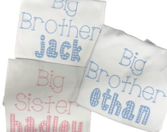 May include: Three white t-shirts featuring embroidered text. Two shirts display the blue text Big Brother with the names Jack and Ethan in blue gingham. One shirt displays the pink text Big Sister with the name hadley in pink gingham.
