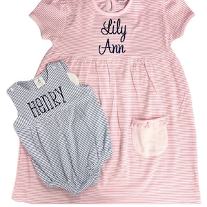 May include: Pink and white striped dress with the name "Lily Ann" embroidered in navy blue. A matching blue and white striped romper with the name "Henry" is also included. Both items are children's clothing.
