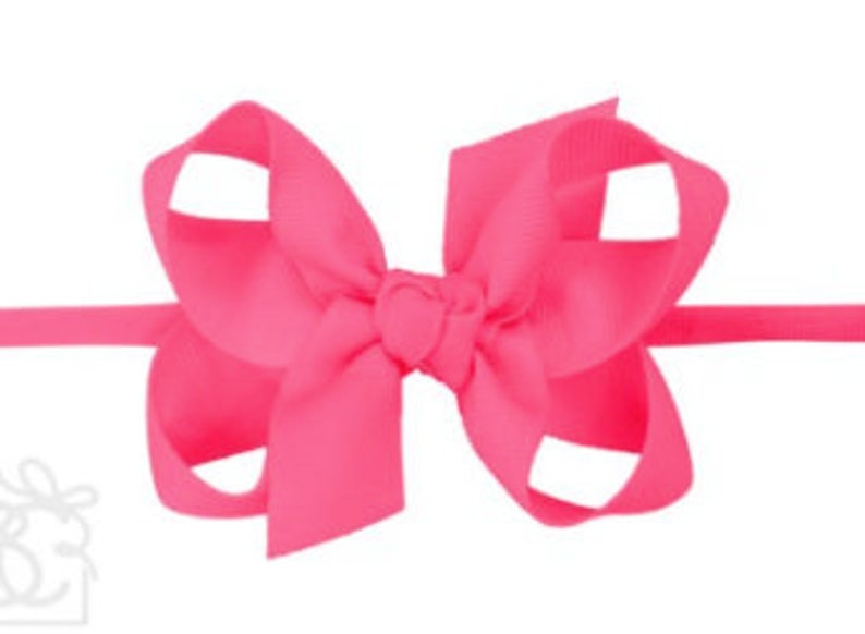 May include: A bright pink hair bow with a simple design. The bow is made of a soft, silky fabric and is tied with a knot in the center.