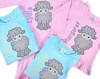 May include: Four personalized baby shirts with a gray and white checkered lamb design. The shirts are in pink and blue colors. The names on the shirts are Lydia, Margaret, Ashford, and Jackson.