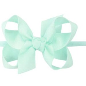 May include: A light blue hair bow with a simple design. The bow is made of a soft, silky material and is tied with a knot in the center.