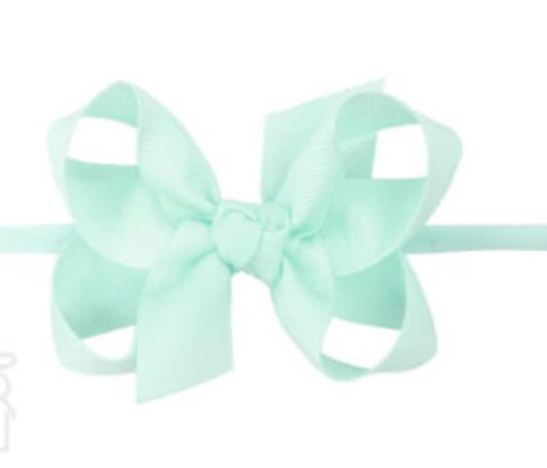 May include: A light blue hair bow with a simple design. The bow is made of a soft, silky material and is tied with a knot in the center.