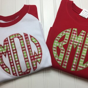 May include: Two red and white shirts with a green and red gingham monogram. The monogram on the white shirt is "MDW" and the monogram on the red shirt is "BML".