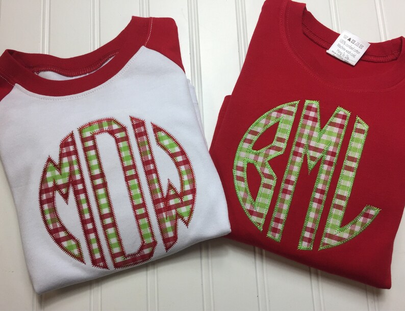 May include: Two red and white shirts with a green and red gingham monogram. The monogram on the white shirt is "MDW" and the monogram on the red shirt is "BML".