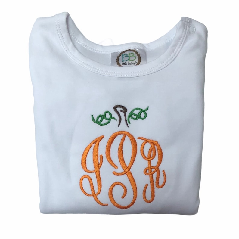 Op de afbeelding: Witte baby romper met een pompoen-vormig monogram in oranje, bruin en groen. Het monogram is de letters "JJB".