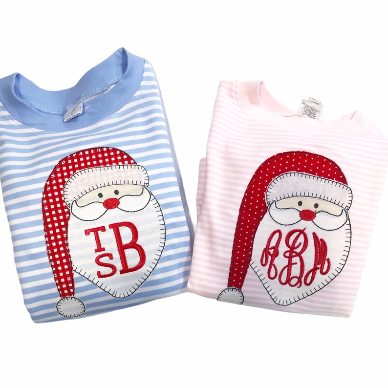 Puede incluir: Dos camisas de manga larga a rayas con caras de Pap&aacute; Noel bordadas. La camisa azul tiene el monograma "TB" y la camisa rosa tiene el monograma "AB".