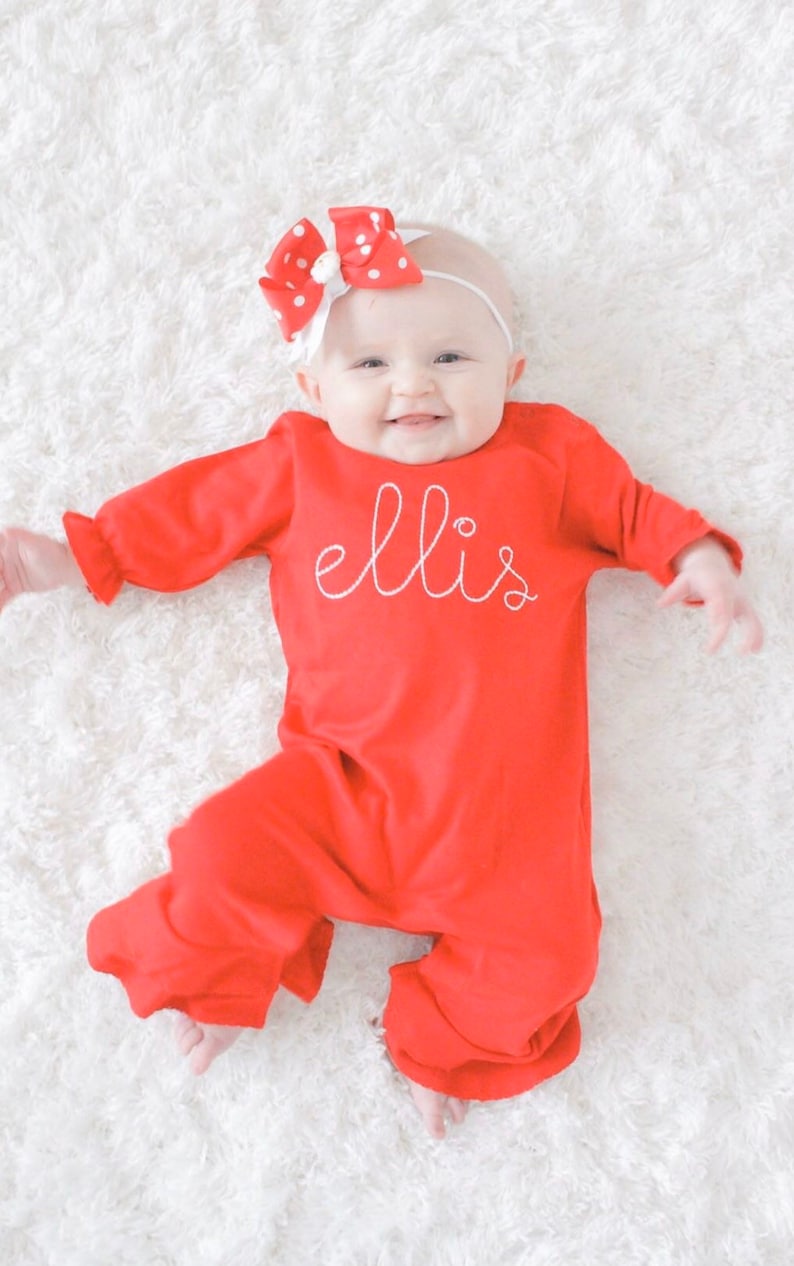 May include: A red baby sleeper with white embroidery that says 'ellis'.