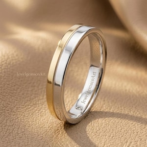 May include: A two-tone ring featuring a polished gold band alongside a polished silver band, with a small embedded diamond visible on the inner surface. The text JewelgemscoArt is printed on the side of the ring and also appears in the background.