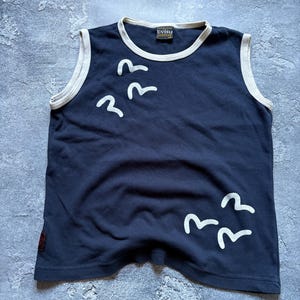 Puede incluir: Romper sin mangas azul marino con ribete blanco y un gr&aacute;fico de p&aacute;jaros blancos. El romper tiene un cuello redondo y una peque&ntilde;a etiqueta con la marca "Evisu". La prenda est&aacute; hecha de un material suave.