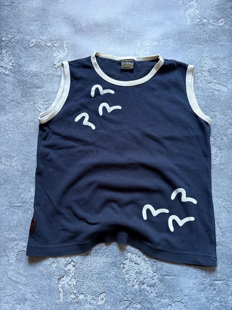 Puede incluir: Romper sin mangas azul marino con ribete blanco y un gr&aacute;fico de p&aacute;jaros blancos. El romper tiene un cuello redondo y una peque&ntilde;a etiqueta con la marca "Evisu". La prenda est&aacute; hecha de un material suave.