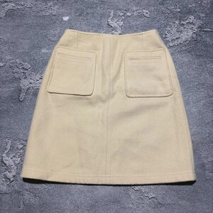 May include: A beige skirt with two large square pockets on the back. The skirt is made of a soft, textured fabric and has a simple, classic design. The skirt is a neutral color and could be paired with many different tops.
