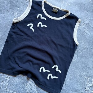 Puede incluir: Top sin mangas azul marino con ribete blanco y gr&aacute;ficos de p&aacute;jaros blancos. El top tiene cuello redondo y una etiqueta que dice "Evisu". La prenda est&aacute; hecha de un material suave.