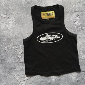 Może przedstawiać: Czarny tank top z białym nadrukiem budynku w owalu. Tank top ma prążkowaną fakturę i małą metkę z napisem "GUERILLAZ". Tank top jest w rozmiarze S.