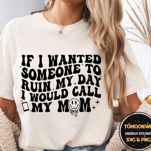 Może przedstawiać: Kremowa koszulka z czarnym napisem: "IF I WANTED SOMEONE TO RUIN MY DAY I WOULD CALL MY MOM". Projekt zawiera ikonę telefonu i topniejącą buźkę. Koszulka pochodzi z TOMOONWB DESIGN STUDIO.