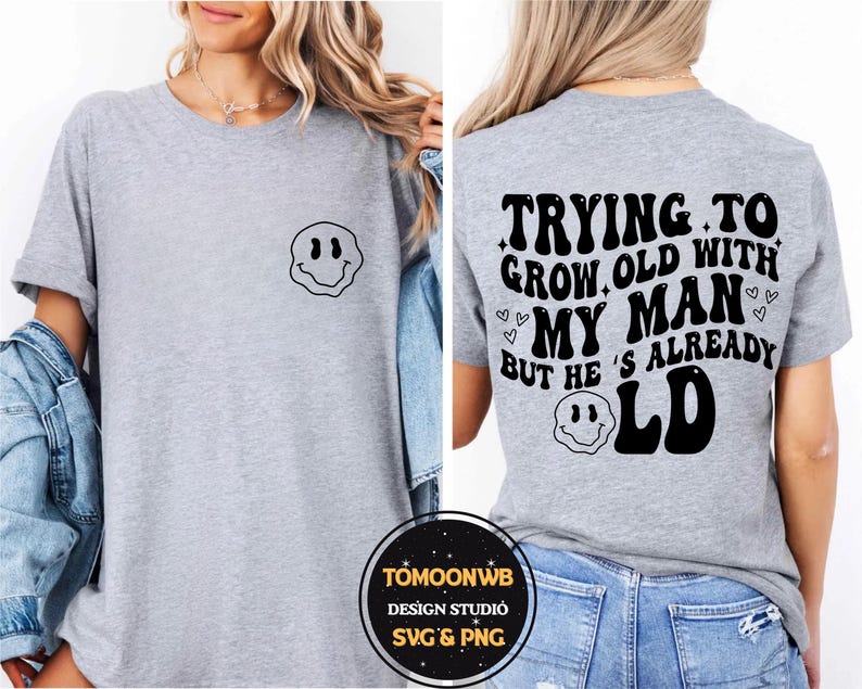 May include: A light gray t-shirt with a black smiley face graphic on the front and the text "TRYING TO GROW OLD WITH MY MAN BUT HE'S ALREADY OLD" on the back. The shirt is a casual style.