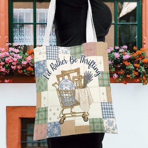 Puede incluir: Un bolso tote de patchwork con el texto "I'd Rather Be Thrifting". El diseño incluye un carrito de compras lleno de platos, marcos y lavanda. La bolsa tiene una variedad de cuadrados de colores pastel.