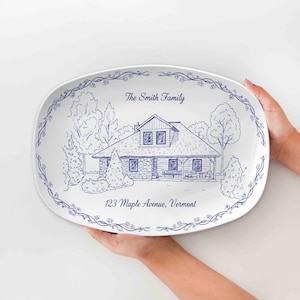 Pode incluir: Travessa oval branca com um desenho a traço azul de uma casa, árvores e uma borda floral. O texto inclui "The Smith Family" e "123 Maple Avenue, Vermont".