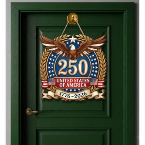 K&ouml;nnte beinhalten: Ein kreisf&ouml;rmiger Wandbehang mit einem Wei&szlig;kopfseeadler mit ausgebreiteten Fl&uuml;geln &uuml;ber der Zahl 250, dem Text UNITED STATES OF AMERICA und den Jahren 1776-2026. Das Design umfasst goldene Lorbeerbl&auml;tter, blaue Akzente, wei&szlig;e Sterne und zwei kleine Flaggen.
