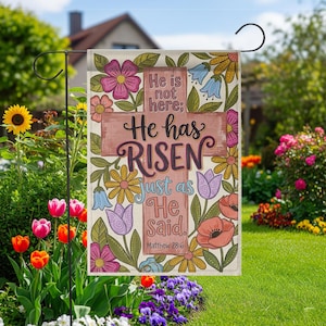 May include: A garden flag with a floral design and the text "He is not here; He has RISEN just as He Said. Matthew 28:6." The flag features a cross and colorful flowers in pink, purple, yellow, and blue.