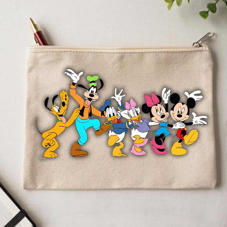 Peut inclure: Une pochette zipp&eacute;e en toile beige avec un graphisme color&eacute; des personnages Disney Pluto, Dingo, Donald Duck, Daisy Duck, Minnie Mouse et Mickey Mouse. Les personnages sont align&eacute;s, les bras lev&eacute;s en signe de c&eacute;l&eacute;bration.