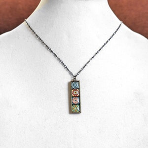 May include: A black chain necklace with a rectangular pendant featuring a colorful mosaic tile design.