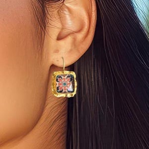 以下が含まれることがあります： カラフルな花柄のゴールドの正方形のイヤリング。イヤリングはフック留めです。