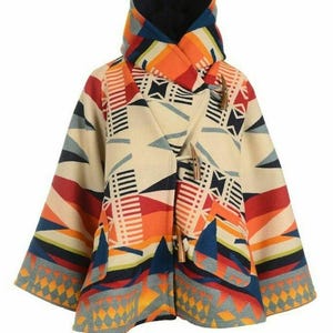 May include: A colorful poncho-style coat with a geometric pattern in shades of orange, red, blue, and cream. The coat features a hood and wooden toggle closures. The sleeves are wide, and the design incorporates triangles and stripes.