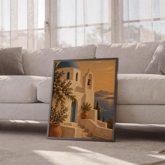 Santorini church wall art print leaning against a white sofa in a bright living room with sheer curtains.