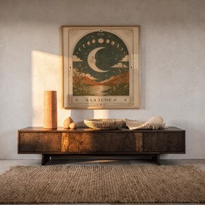 Terracotta spiritual moon tarot art framed on dark wooden console table in warm sunlit room.