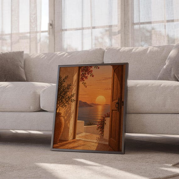 Mediterranean sunset doorway wall art print leaning against a white sofa in a bright living room with sheer curtains.