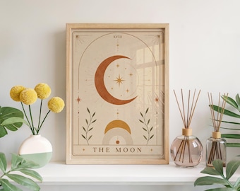 以下が含まれることがあります： THE MOONというタイトルの額入りアートプリント。テラコッタ色の大きな三日月、小さな金色の太陽、そして星と葉の繊細なイラストが、薄いベージュの背景に左右対称の構図で描かれています。