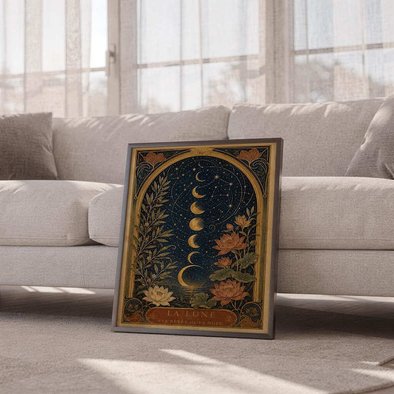 Moon phase wall art print leaning against a white sofa in a bright living room with sheer curtains.
