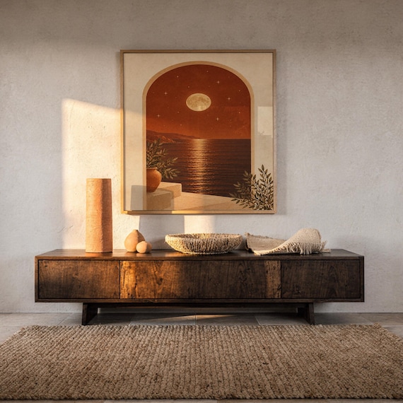 Moonlit Mediterranean arch print hanging above a dark wood console and jute rug in a warm neutral interior.