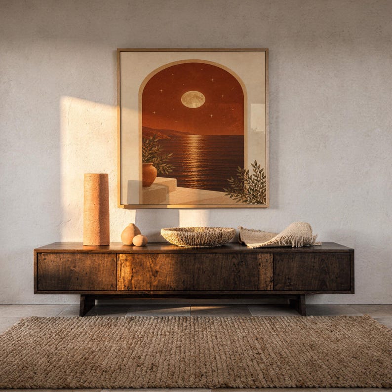 Moonlit Mediterranean arch print hanging above a dark wood console and jute rug in a warm neutral interior.