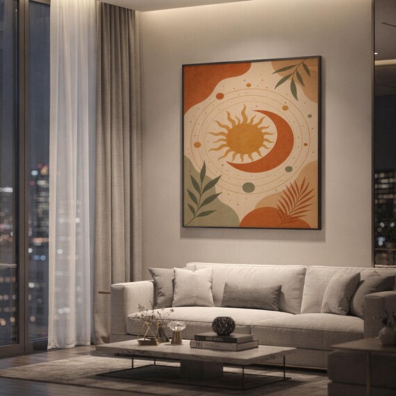 Celestial sun and moon art print showing a radiant sun and crescent moon with orbiting planets and leaves in terracotta, golden ochre, sage and cream, hanging above a light gray sofa in a modern living room with evening city views through tall windows.