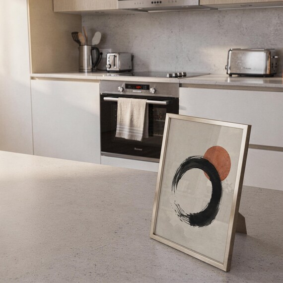Framed zen circle poster leaning against the wall on a clean white kitchen island counter.