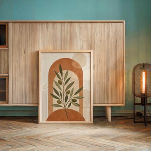 Minimalist olive branch print leaning against light wooden sideboard cabinet