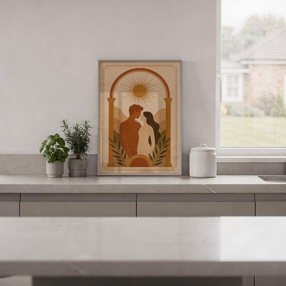 Framed arch silhouette art print displayed on a bright white kitchen island counter with green potted plants and garden view.