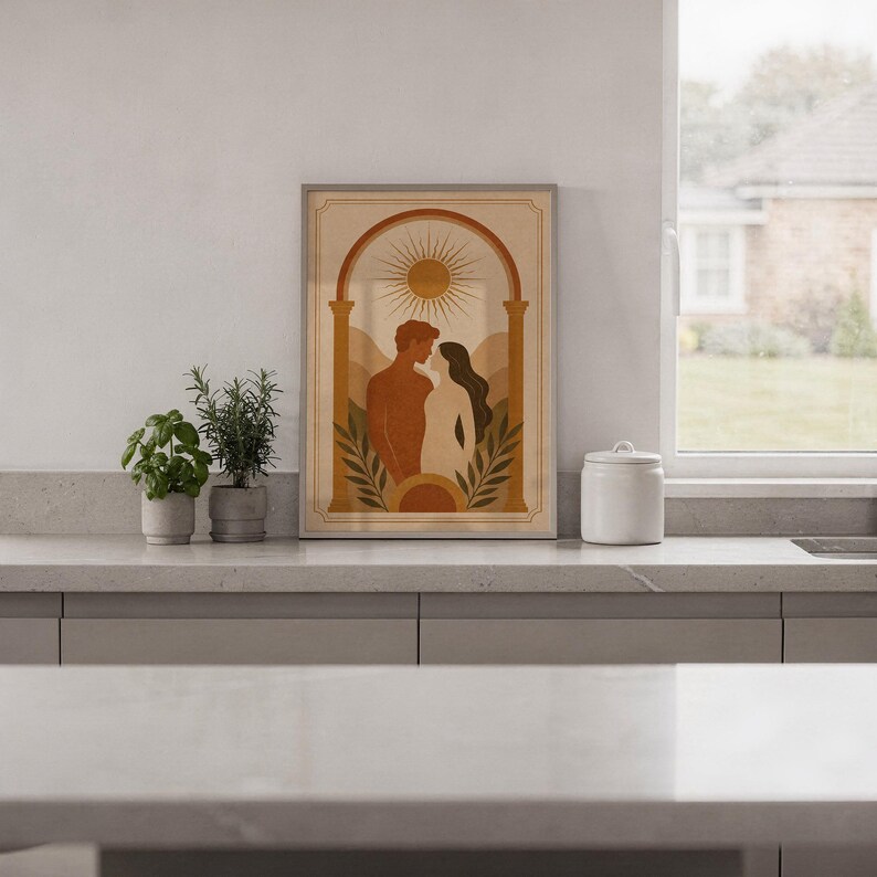 Framed arch silhouette art print displayed on a bright white kitchen island counter with green potted plants and garden view.