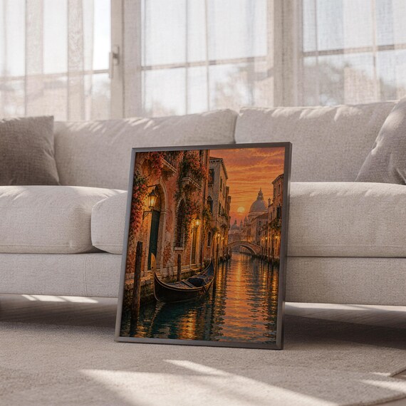 Venice canal sunset wall art print leaning against a white sofa in a bright living room with sheer curtains.