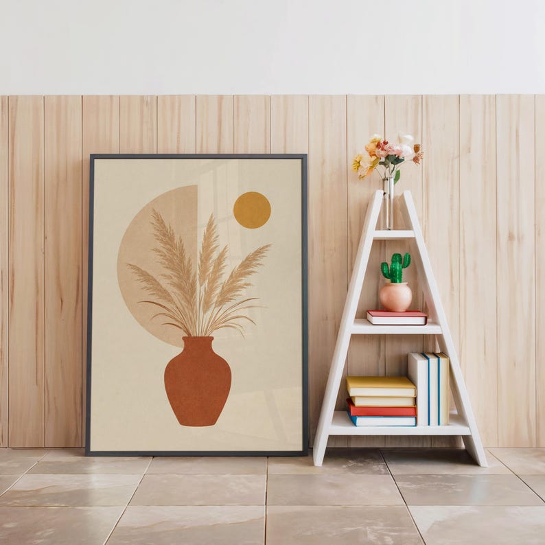 Boho pampas grass art in black frame beside white decorative ladder shelf