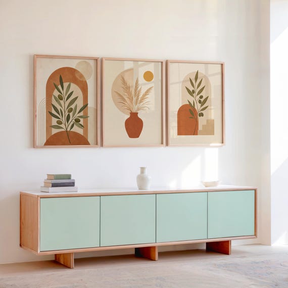 Set of 3 framed earthy botanical prints displayed above a wooden sideboard console.
