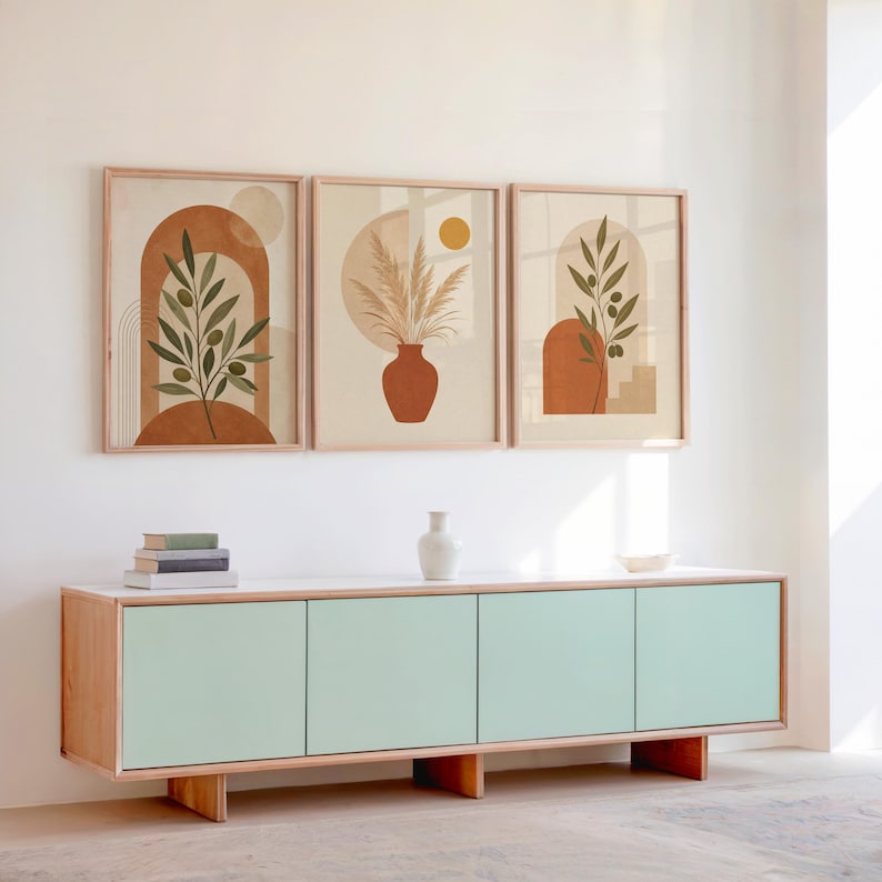 Set of 3 framed earthy botanical prints displayed above a wooden sideboard console.