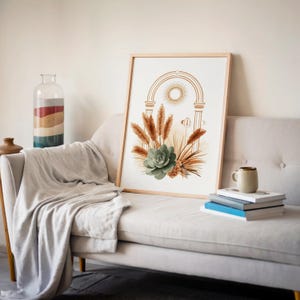Boho arch wall art poster leaning on a light gray sofa backrest with a soft draped blanket, books on a side table, and minimalist wall decor in a modern cozy apartment living room.
