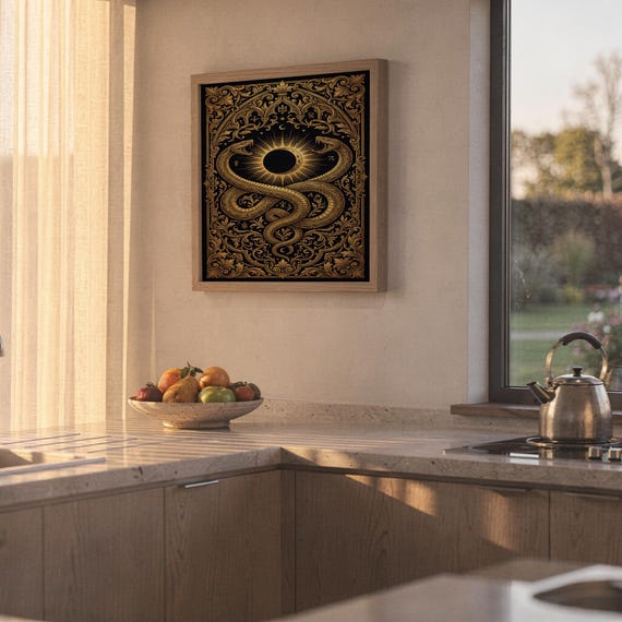 Occult snake wall art print hanging above a stone countertop with a fruit bowl in a sunny kitchen.