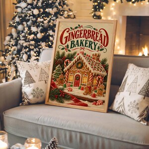 Gingerbread bakery christmas wall art print in a white frame leaning against a gray sofa on a sunlit wooden floor.