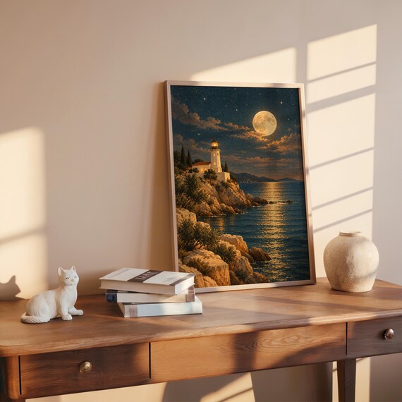 Moonlit lighthouse wall art print leaning on a wooden desk against a warm beige wall in soft window sunlight.
